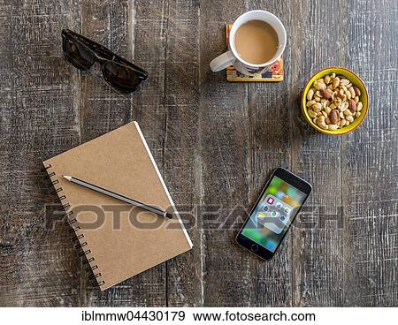Smartphone, notebook with pen, sunglasses, coffee and nuts, snacks on a wooden table View Large Photo Image Stock Photo - Smartphone, notebook with pen, sunglasses, coffee and nuts, snacks on a wooden table. Fotosearch