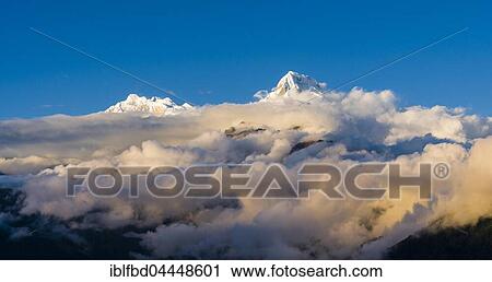Snow-covered summits of Annapurna 1, right and Annapurna South, left, with monsoon clouds, seen from Poon Hill, Ghorepani, Myagdi District, Nepal, Asia View Large Photo Image Stock Image - Snow-covered summits of Annapurna 1, right and Annapurna South, left, with monsoon clouds, seen from Poon Hill, Ghorepani, Myagdi District, Nepal, Asia. Fotosearch