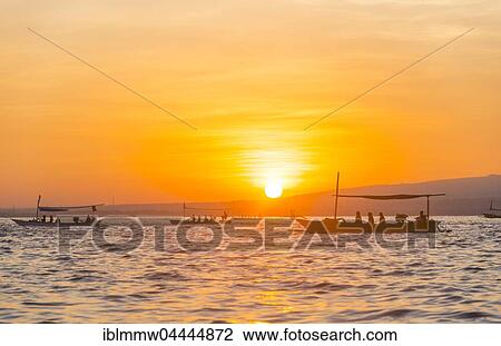 Stock Image - Sunrise, outrigger canoes in the sea, Lovina Beach, Bali, Indonesia, Asia. Fotosearch