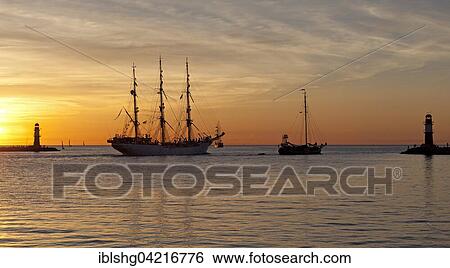 Sunset at harbor entrance, backlit sailboats, Hanse-Sail, Rostock, Mecklenburg-Western Pomerania, Germany, Europe View Large Photo Image Stock Photograph - Sunset at harbor entrance, backlit sailboats, Hanse-Sail, Rostock, Mecklenburg-Western Pomerania, Germany, Europe. Fotosearch