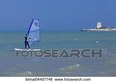 Stock Photograph - Surfer on the sea, Baia di Sfinale bay, behind Torre di Sfinale, Gargano, Foggia, Apulia, Italy, Europe. Fotosearch