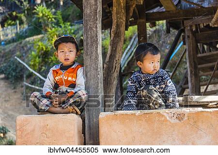 Stock Photography - Two little boys sitting at log cabin, Palaung hilltribe, Palaung Village in Kyaukme, Shan State, Myanmar, Asia. Fotosearch