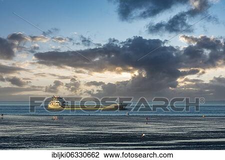 Stock Image - Unloaded cargo ship on the world shipping route Elbe at the Wadden Sea, Cuxhaven, Lower Saxony, Germany, Europe. Fotosearch