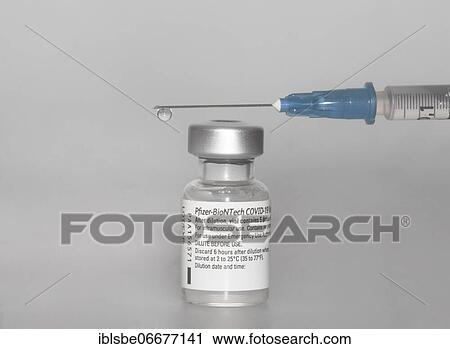 Stock Image - Vaccine vial against Covid 19 and syringe with drops, Biontech, Pfizer, Pfizer-BioNTech. Fotosearch
