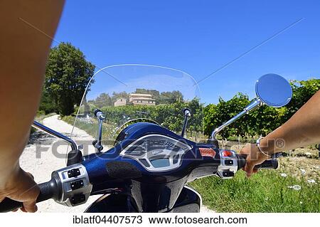 Woman holding handlebars of Vespa Primavera scooter traveling in the Sant'Amico wine country, Morro D'Alba, Marche, Italy, Europe View Large Photo Image Stock Image - Woman holding handlebars of Vespa Primavera scooter traveling in the Sant'Amico wine country, Morro D'Alba, Marche, Italy, Europe. Fotosearch