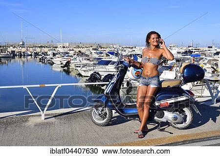 Woman in bikini top with mobile phone leaning against a Vespa Primavera scooter, Senigallia, Adriatic coast, Marche, Italy, Europe View Large Photo Image Stock Image - Woman in bikini top with mobile phone leaning against a Vespa Primavera scooter, Senigallia, Adriatic coast, Marche, Italy, Europe. Fotosearch