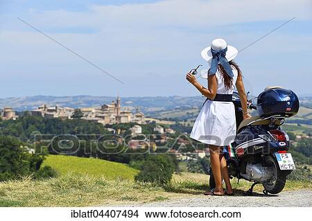 Woman with white sunhat next to Vespa Primavera scooter, Corinaldo, Marche, Italy, Europe View Large Photo Image Picture - Woman with white sunhat next to Vespa Primavera scooter, Corinaldo, Marche, Italy, Europe. Fotosearch