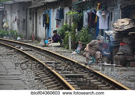 Stock Image - Women at buildings near train tracks, Hanoi, Vietnam, Asia. Fotosearch