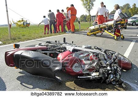 Stock Image - Wrecked motorcycle on road, traffic accident, casualty being taken to helicopter by rescue service, Markt Swabia, Upper Bavaria, Bavaria, Germany, Europe. Fotosearch