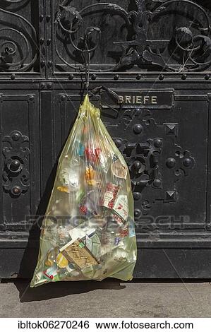 Stock Photograph - Yellow bag for plastic waste, hanging on front door, Germany, Europe. Fotosearch