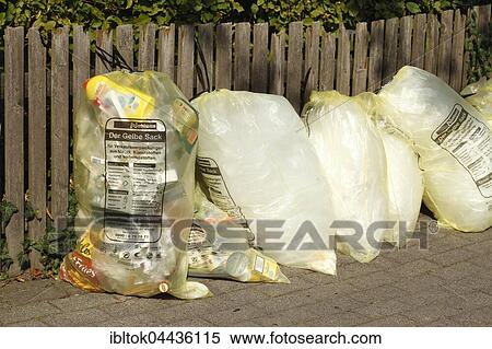 Stock Photography - Yellow bags with plastic waste, hanging on garden fence, waste separation, Lower Saxony, Germany, Europe. Fotosearch