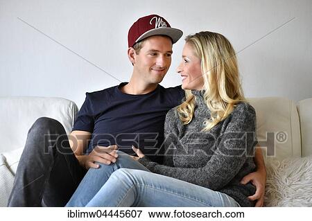 Young couple, lovers sitting on sofa, looking at each other View Large Photo Image Stock Photo - Young couple, lovers sitting on sofa, looking at each other. Fotosearch