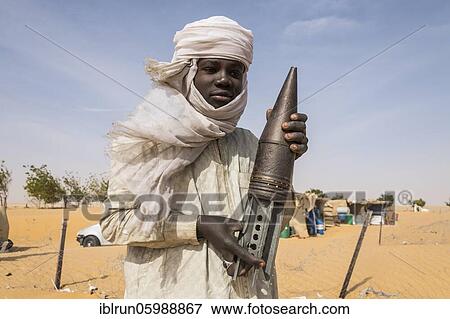 Stock Photo - Young Man posing with an old rockethead, between Faya-Largeaux and N'Djamena, Sahara, Chad, Africa. Fotosearch