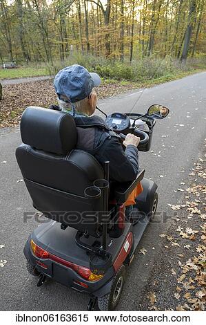 Stock Photography - 92-year-old pensioner rides electric wheelchair on road, Germany, Europe. Fotosearch