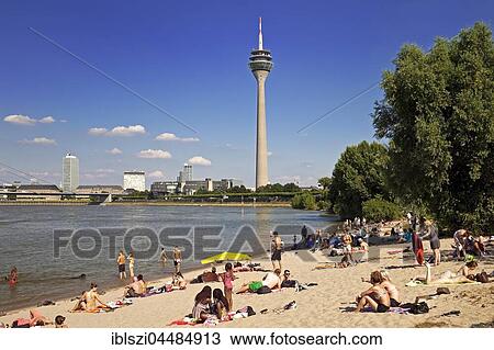 Stock Image - Bathers on the beach on the Rhine with Rhine Tower, Düsseldorf, North Rhine-Westphalia, Germany, Europe. Fotosearch