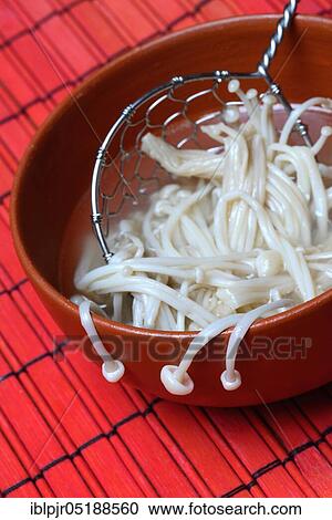 Stock Image - Boiled Golden needle mushroommushrooms in bowl with strainer,, metal strainer. Fotosearch