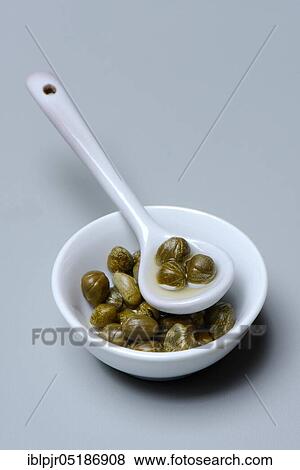 Stock Photo - Bowl and porcelain spoon with capers, inlaid ( Capparis spinosa). Fotosearch