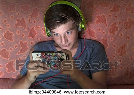 Boy, 12 years old, listening to music with headphones on a smartphone, Germany, Europe View Large Photo Image Stock Photograph - Boy, 12 years old, listening to music with headphones on a smartphone, Germany, Europe. Fotosearch