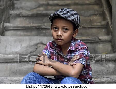 Stock Image - Boy on staircase with shirt and flat cap, Phnom Penh Province, Cambodia, Asia. Fotosearch