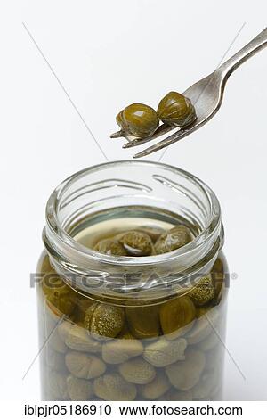 Stock Image - Capers on fork and glass with inlaid capers, inlaid ( Capparis spinosa). Fotosearch