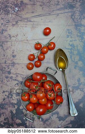 Stock Image - Cherry tomatoes in peel and spoon with olive oil, Solanum lycopersicum, cherry tomato, cherry tomatoes. Fotosearch