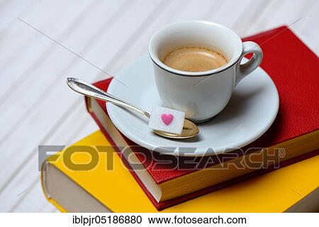 Stock Image - Coffee cup on books and coffee spoon with sugar cubes, espresso. Fotosearch
