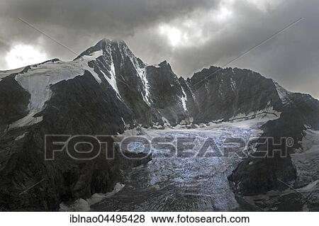 Stock Photo - Dramatic cloud atmosphere at Grossglockner and Pasterze, High Tauern National Park, Carinthia, Austria, Europe. Fotosearch