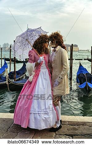 Stock Photo - Dressed up couple with masks standing in front of the lagoon, Venice Carnival, St. Mark's Square, Venice, Veneto, Italy, Europe. Fotosearch