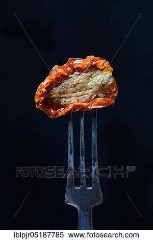 Stock Photography - Dried tomato on fork, Lycopersicon esculentum, Solanum lycopersicum. Fotosearch