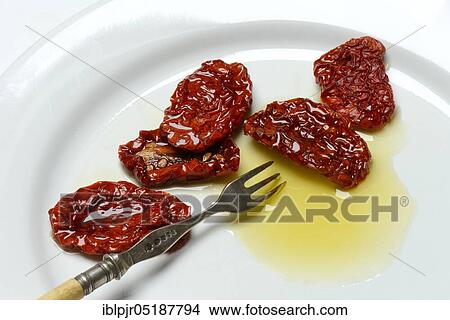 Dried tomatoes in olive oil on plate with fork, Solanum lycopersicum View Large Photo Image Picture - Dried tomatoes in olive oil on plate with fork, Solanum lycopersicum. Fotosearch