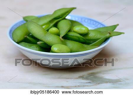 Stock Image - Edamame, cooked unripe Soya beans (Glycine max) in a bowl. Fotosearch