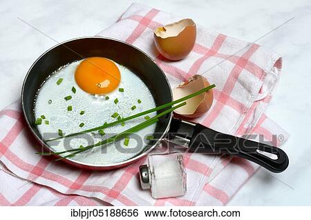 Stock Photograph - Fried egg with chives in frying pan. Fotosearch
