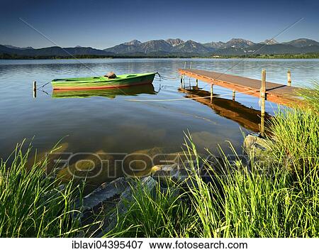Stock Photo - Green boat at the dock, Hopfensee, in front of the Allgäu Alps, Allgäu, Bavaria, Germany, Europe. Fotosearch