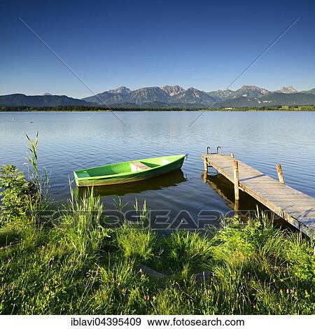 Stock Photo - Green boat at the dock, Hopfensee, in front of the Allgäu Alps, Allgäu, Bavaria, Germany, Europe. Fotosearch