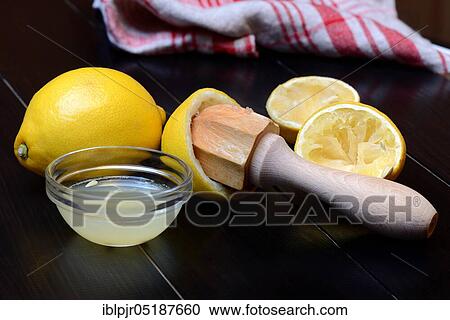 Stock Image - Lemon, lemon juice in peel and lemon squeezer. Fotosearch
