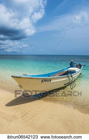 Stock Image - Little motorboat in the turquoise waters of Banana beach, Unesco biosphere reserve, Principe, Sao Tome and Principe, Atlantic Ocean, Africa. Fotosearch
