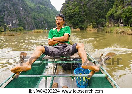 Local man rowing with his feet on the Ngo Dong River, Song Ngô Dong, Tam Coc, Ninh Binh, Vietnam, Asia View Large Photo Image Picture - Local man rowing with his feet on the Ngo Dong River, Song Ngô Dong, Tam Coc, Ninh Binh, Vietnam, Asia. Fotosearch