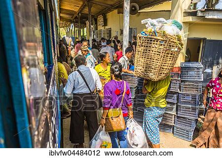 Stock Image - Locals boarding train on platform, Yangon Circular Railway, Yangon, Myanmar, Asia. Fotosearch
