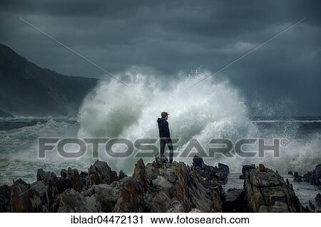 Man on rock in front of breaking wave, surf on rocky coast, Tsitsikamma National Park, South Africa, Africa View Large Photo Image Stock Image - Man on rock in front of breaking wave, surf on rocky coast, Tsitsikamma National Park, South Africa, Africa. Fotosearch