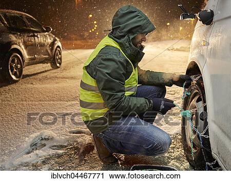 Man with safety vest applying snow chains on snow-covered road, Wattens, Tyrol, Austria, Europe View Large Photo Image Stock Image - Man with safety vest applying snow chains on snow-covered road, Wattens, Tyrol, Austria, Europe. Fotosearch
