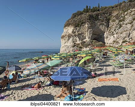 Stock Image - Many people with colorful sunshades at Lido Isola Bella Beach, Tropea, Calabria, Italy, Europe. Fotosearch