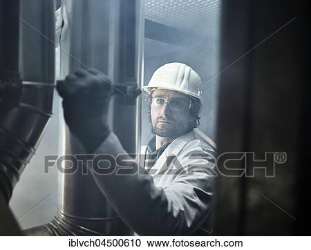 Stock Image - Mechanic with white helmet and lab coat moving a lever of a refrigerant line, Austria, Europe. Fotosearch