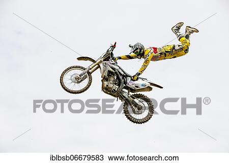 Stock Image - Motocross rider jumping in front of cloudy sky, Biberach, Baden-Württemberg, Germany, Europe. Fotosearch