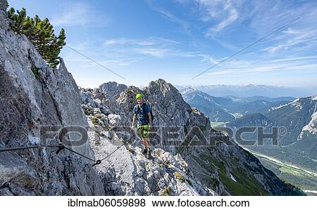Mountaineer climbs on a secured fixed rope route, Mittenwalder Höhenweg, view into the Isar valley near Mittenwald, Karwendel Mountains, Mittenwald, Bavaria, Germany, Europe View Large Photo Image Stock Photo - Mountaineer climbs on a secured fixed rope route, Mittenwalder Höhenweg, view into the Isar valley near Mittenwald, Karwendel Mountains, Mittenwald, Bavaria, Germany, Europe. Fotosearch