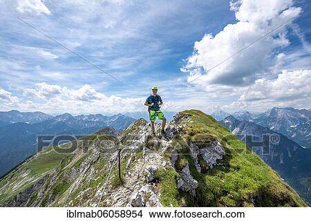 Mountaineer on a ridge on a secured fixed rope route, Mittenwalder Höhenweg, view of mountain panorama, Karwendel Mountains, Mittenwald, Bavaria, Germany, Europe View Large Photo Image Picture - Mountaineer on a ridge on a secured fixed rope route, Mittenwalder Höhenweg, view of mountain panorama, Karwendel Mountains, Mittenwald, Bavaria, Germany, Europe. Fotosearch