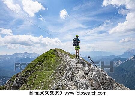 Stock Photo - Mountaineer on a ridge on a secured fixed rope route, Mittenwalder Höhenweg, view of mountain panorama, Karwendel Mountains, Mittenwald, Bavaria, Germany, Europe. Fotosearch