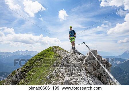Stock Photo - Mountaineer on a ridge on a secured fixed rope route, Mittenwalder Höhenweg, view of mountain panorama, Karwendel Mountains, Mittenwald, Bavaria, Germany, Europe. Fotosearch