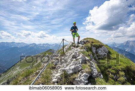 Stock Photography - Mountaineer on a ridge on a secured fixed rope route, Mittenwalder Höhenweg, view of mountain panorama, Karwendel Mountains, Mittenwald, Bavaria, Germany, Europe. Fotosearch