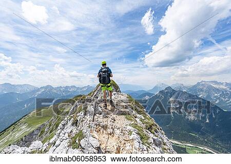 Stock Image - Mountaineer on a ridge on a secured via ferrata, Mittenwalder Höhenweg, view into the Isar valley near Mittenwald, Karwendel Mountains, Mittenwald, Bavaria, Germany, Europe. Fotosearch
