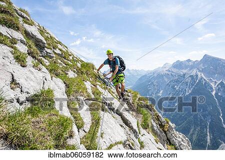 Stock Image - Mountaineer on a secured via ferrata, Mittenwalder Höhenweg, view of mountain panorama, Karwendel Mountains, Mittenwald, Bavaria, Germany, Europe. Fotosearch